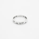 Silver ring with engraved design on a white background, close up top down view